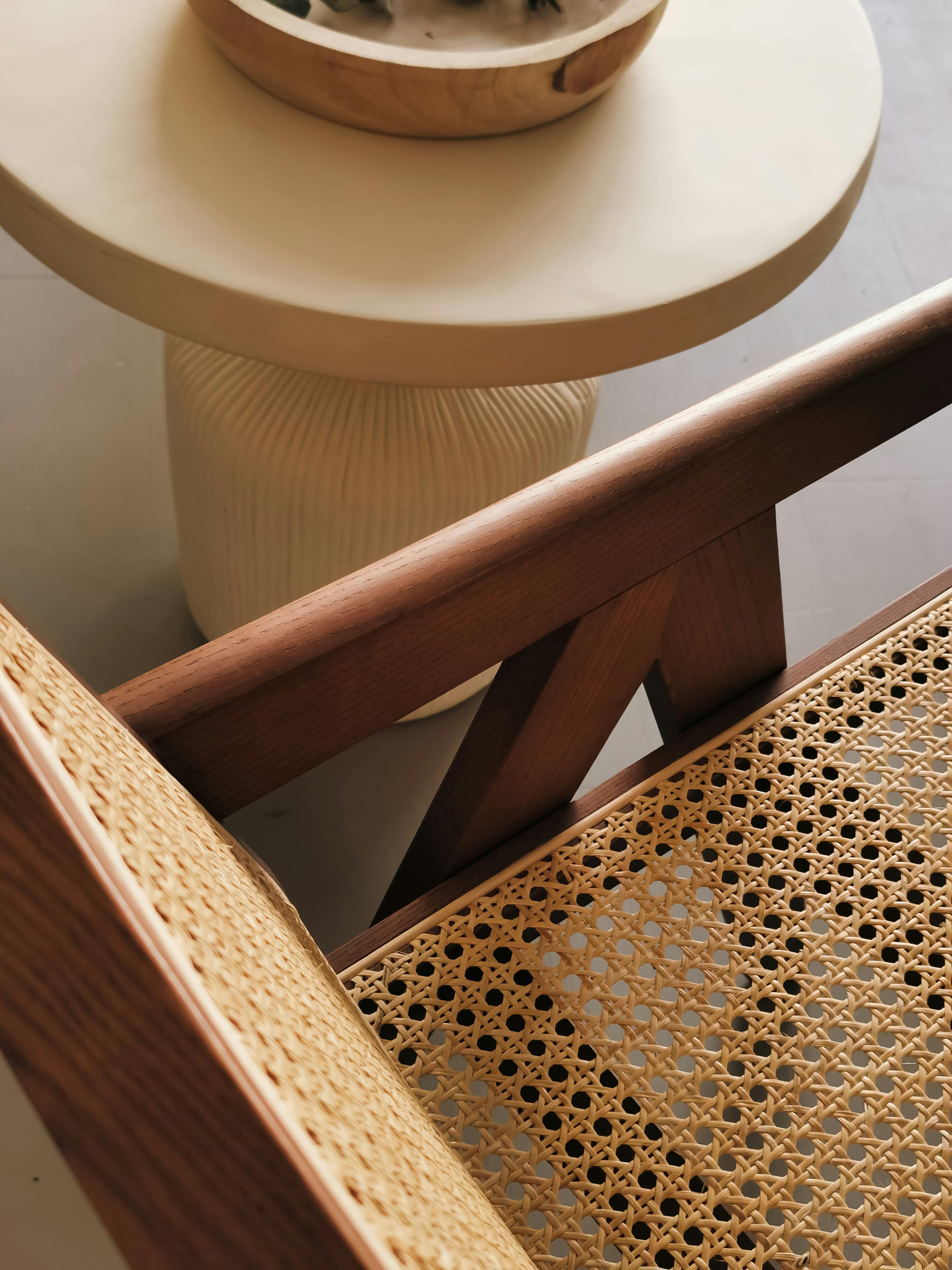 Close-up of a handcrafted rattan chair with wooden frame next to a round bamboo side table – EcoLuxLiven sustainable furniture
